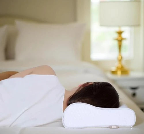 Person sleeping on side with orthopedic pillow supporting neck and spine alignment in cozy bedroom