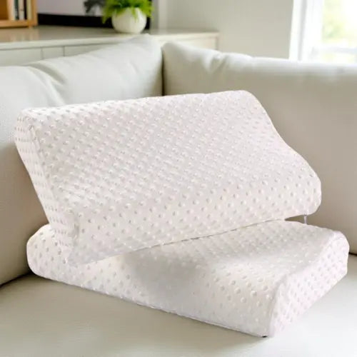 Two white ergonomic memory foam pillows stacked on beige sofa, ideal for home relaxation or travel use